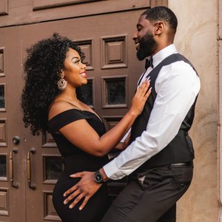 woman in black dress standing beside man in white suit jacket